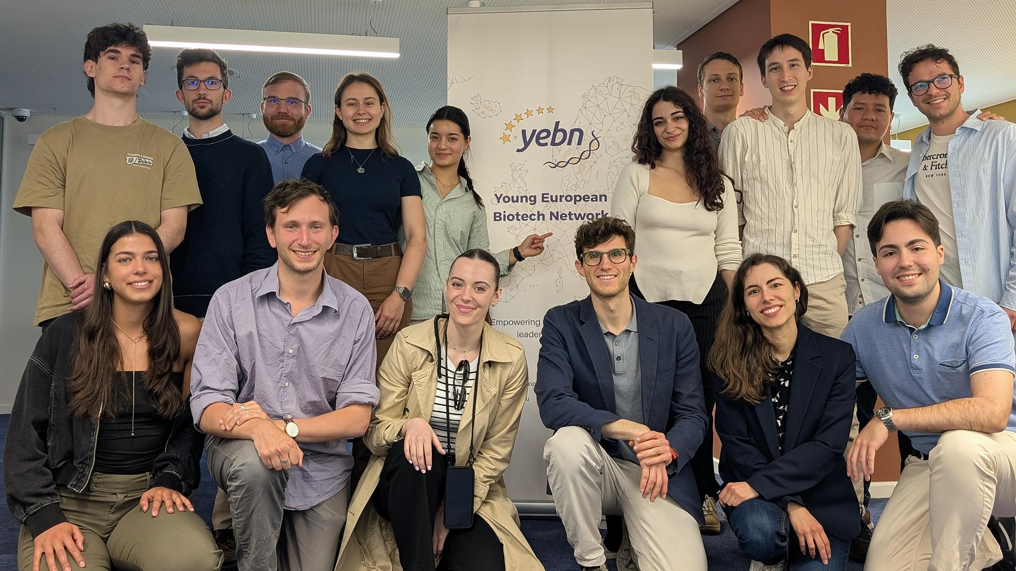 Sixteen YEBN members together at a network meeting, in front of the YEBN banner.